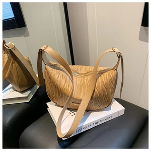 Detail of beige pleated croissant bag with gold zipper and stylish metal ring strap