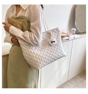 Détail du grand sac cabas blanc matelassé avec un pendentif peluche et bandoulière fine