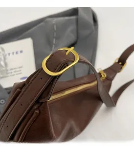 Detail of dark brown leather shoulder bag featuring vintage gold metal buckle and hardware
