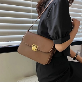 Détail du sac à bandoulière en cuir marron avec boucle en métal doré sur modèle