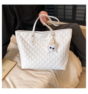 Détail d'un cabas blanc matelassé en similicuir avec un charmant pendentif peluche
