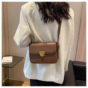Sac à bandoulière en cuir PU marron avec boucle dorée et fine lanière porté par mannequin