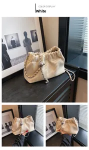 Detailed texture of white corduroy bucket bag with silver metal chain and ball charm