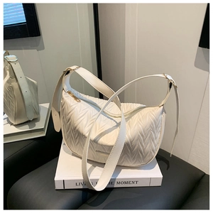 Detail view of white pleated leather texture and gold hardware on minimalist shoulder bag