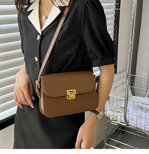 Détail de sac bandoulière marron avec fermoir doré porté par un mannequin
