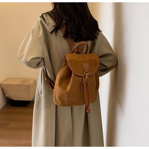 Detailed back view of a brown frosted suede mini backpack worn with a stylish trench coat