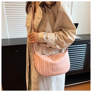 Detailed shot of pink pleated crescent bag with adjustable strap and brand tag