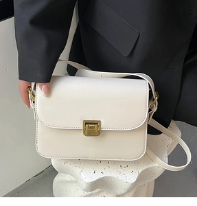 Détail du sac à bandoulière beige avec fermoir en métal doré sur surface texturée