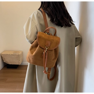 Side view of a vintage brown frosted leather backpack shown on a model in a minimal room