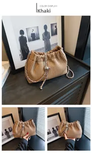 Detailed close-up of khaki pleated bucket bag featuring elegant metal chain and corduroy texture