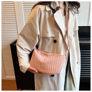 Detail of pink pleated crossbody bag featuring wavy texture and adjustable strap