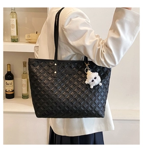 Détail du sac cabas matelassé noir à motif losanges avec charme en peluche blanche