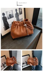 Detail of brown pleated bucket bag with silver metal chain and decorative ball
