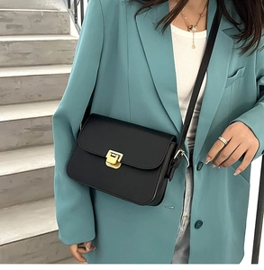 Détail d'un sac à bandoulière noir mat avec boucle métallique carrée dorée classique