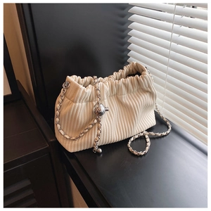 Detail of beige corduroy cloud bag with metal chain strap and spherical gold accent