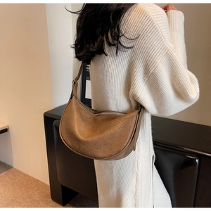 Retro brown crescent shoulder bag with pleated leather texture on a white knit sweater