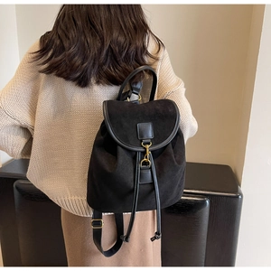 Detail of vintage matte black backpack with drawstring closure and golden metal hook