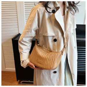 Close-up of beige pleated crossbody bag with leather logo patch and metal zipper