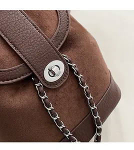 Detail of silver twist lock and mixed leather textures on a brown bucket handbag