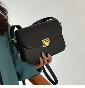 Gros plan d'un sac à bandoulière en cuir noir vintage avec un fermoir en métal doré