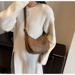 Close-up of brown crescent crossbody bag featuring soft crinkled texture and gold buckles