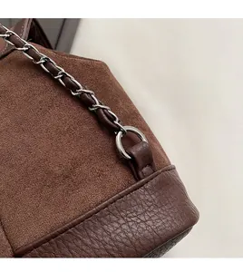 Detail showing high-quality silver chain strap and brown spliced suede texture of bag