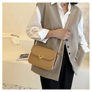 Borsa a tracolla kaki alla moda con fibbia dorata indossata da modella su scale