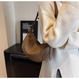 Detail of vintage brown crescent bag in pleated leather worn over a white sweater