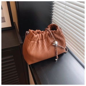 Close-up of brown pleated bucket bag featuring a silver chain and textured metal ball