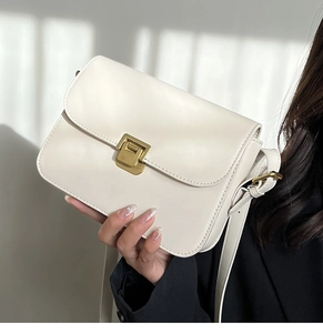 Détail d'un sac bandoulière blanc crème montrant la boucle dorée et le cuir lisse