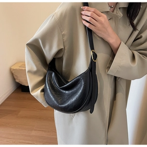 Detail of black pebbled leather texture on hobo bag with gold adjustable buckle