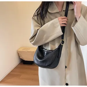 Detail of black crescent crossbody bag with silver zipper and textured faux leather