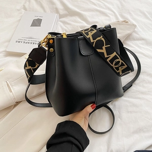 Sac seau chic en cuir noir mat avec bandoulière jacquard et détails dorés brillants