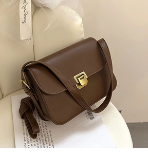 Détail d'un sac bandoulière en cuir marron foncé avec boucle en métal doré vintage