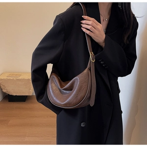 Close-up of brown crescent bag with retro pleated texture and golden metal buckle