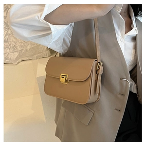 Dettaglio di borsa a tracolla beige in pelle con fibbia quadrata dorata e tracolla fine
