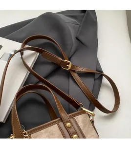 Detail of adjustable leather shoulder strap with golden buckles on a vintage tote bag
