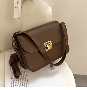 Détail d'un sac à bandoulière marron vintage avec boucle dorée et deux sangles réglables