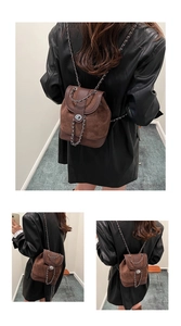 Detail of a brown suede bucket backpack with metal chain straps and a round swivel lock