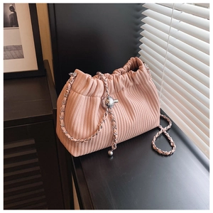 Chic pink pleated bucket bag with silver chain strap and metal ball charm on wood