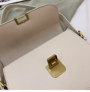 Détail du sac bandoulière blanc cassé montrant la boucle dorée et l'espace intérieur