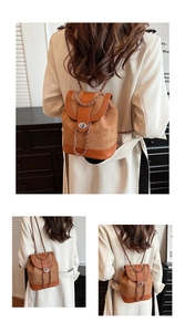 Detail of brown faux suede backpack featuring metallic twist lock and chain shoulder strap