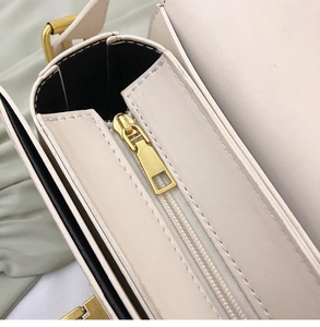 Détail du sac bandoulière en cuir beige clair avec fermeture éclair dorée et garnitures