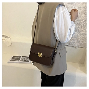 Dettaglio borsa sottobraccio in pelle marrone scuro con chiusura in metallo dorato vintage