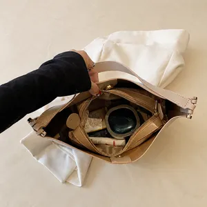 Internal view of beige shoulder bag showing main compartment and zippered pocket