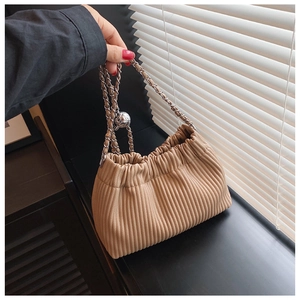 Close-up of khaki pleated bucket bag featuring vertical textures and silver chain strap