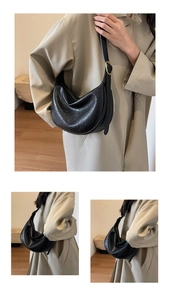 Macro detail of black leather crescent bag with vintage texture and gold metallic buckle