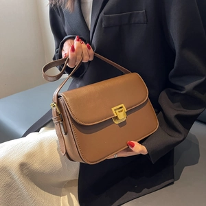 Sac bandoulière marron en cuir PU avec boucle dorée porté par un mannequin élégant