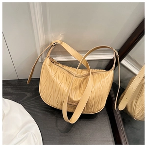 Detail of ruched beige crescent shoulder bag showing fine leather pleats and metallic zipper