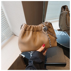 Detail of khaki pleated bucket bag with metal chain strap and spherical hardware decoration